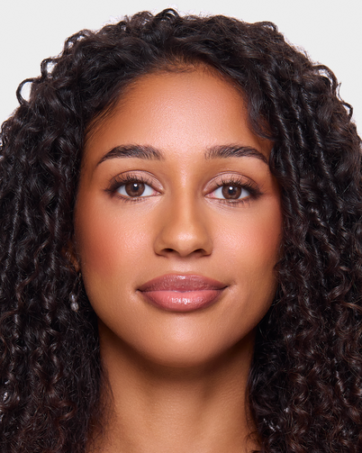 Woman with curly hair against a plain background wearing Dimple Color's Serenity Brown colour contact lenses